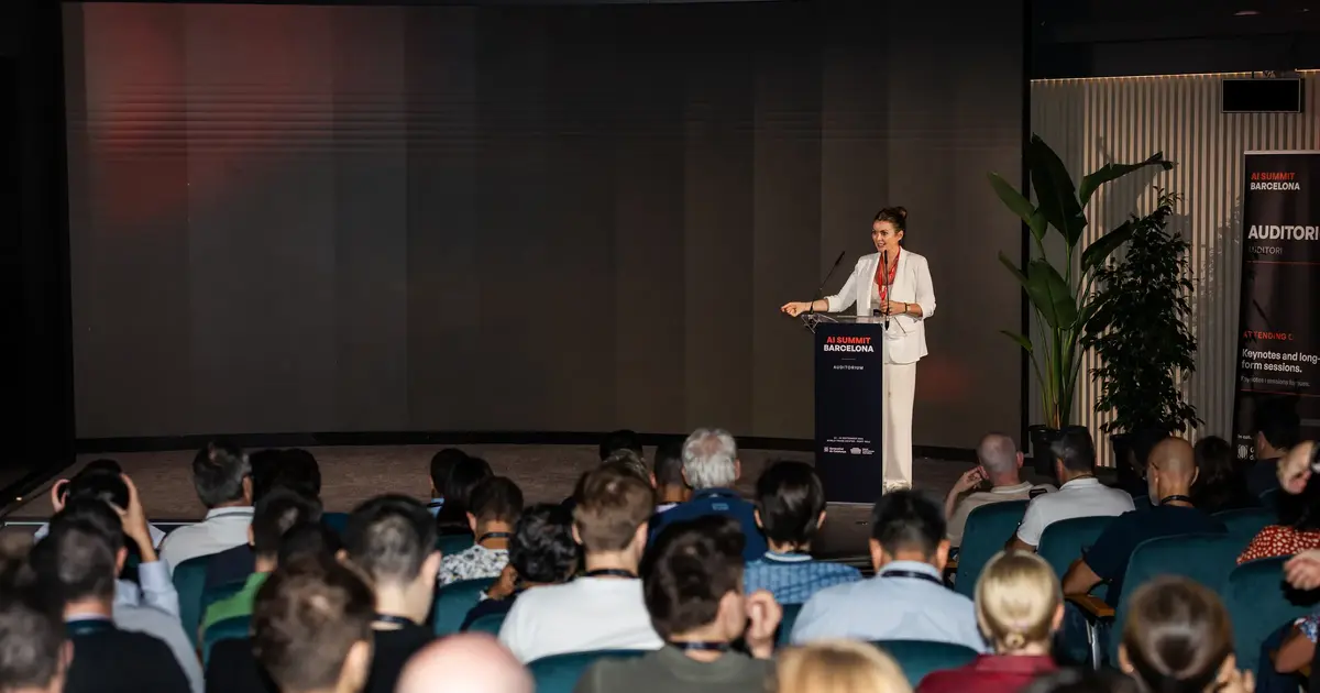 A speaker addressing the seated audience from the Summit stage.