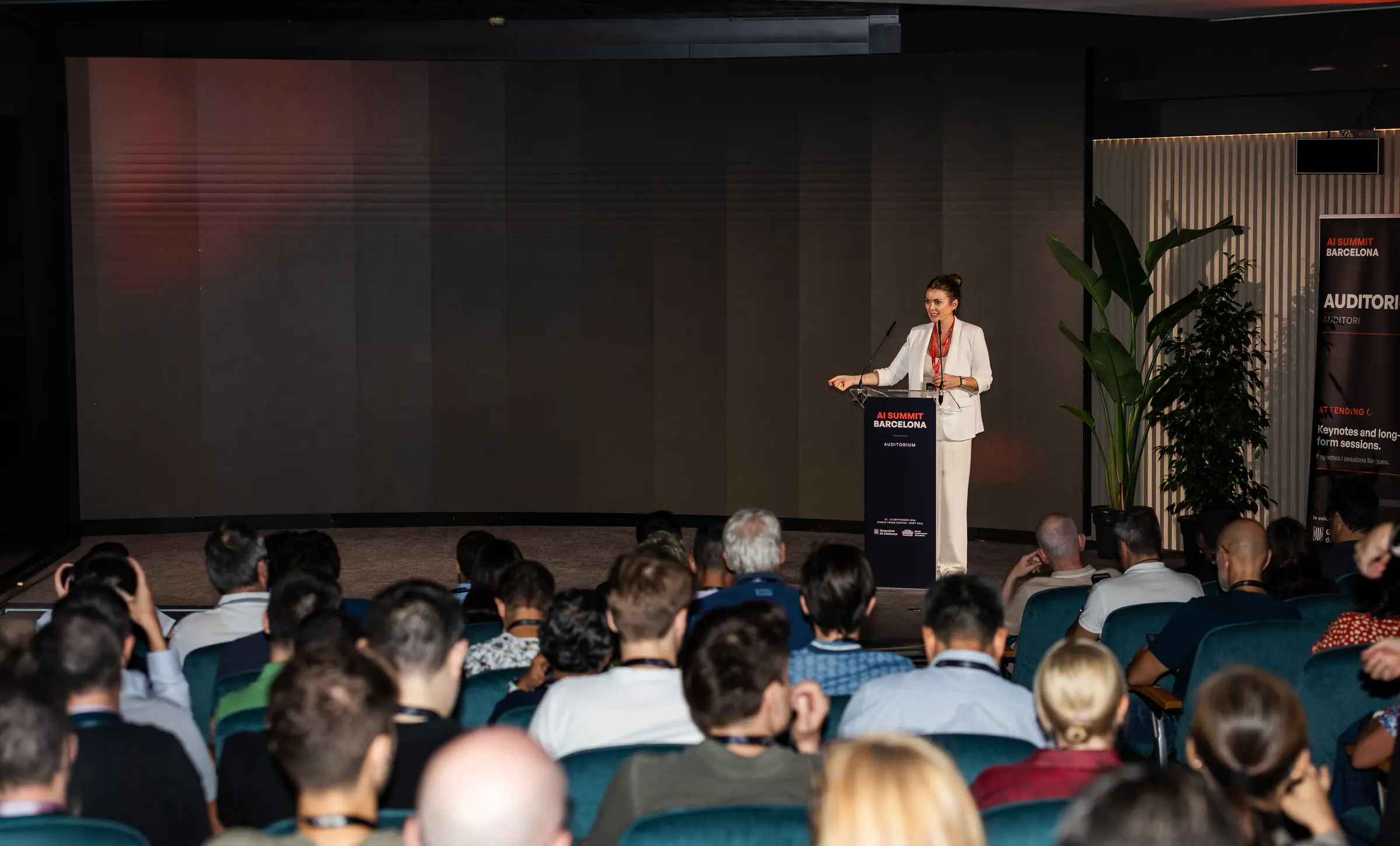 A speaker at the AI Summit Barcelona Auditorium lectern in front of a full audience